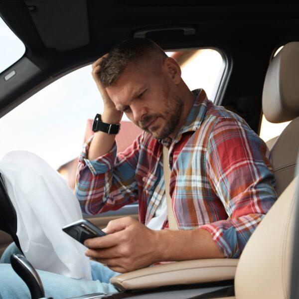 Man sitting in the driver’s seat of his car with the airbag deployed following an auto crash and wondering when it is too late to get a lawyer for a car accident.