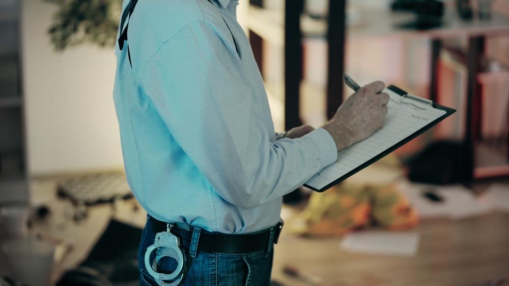 A police officer filling out a form on a clipboard who can explain how to get a police report for a car accident in Kansas City.
