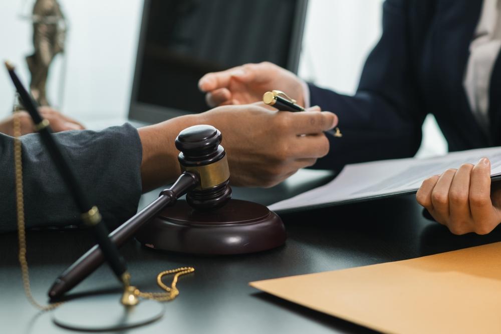 Two people go over legal papers near a gavel as they discuss whether a lawsuit can be reopened after settlement.