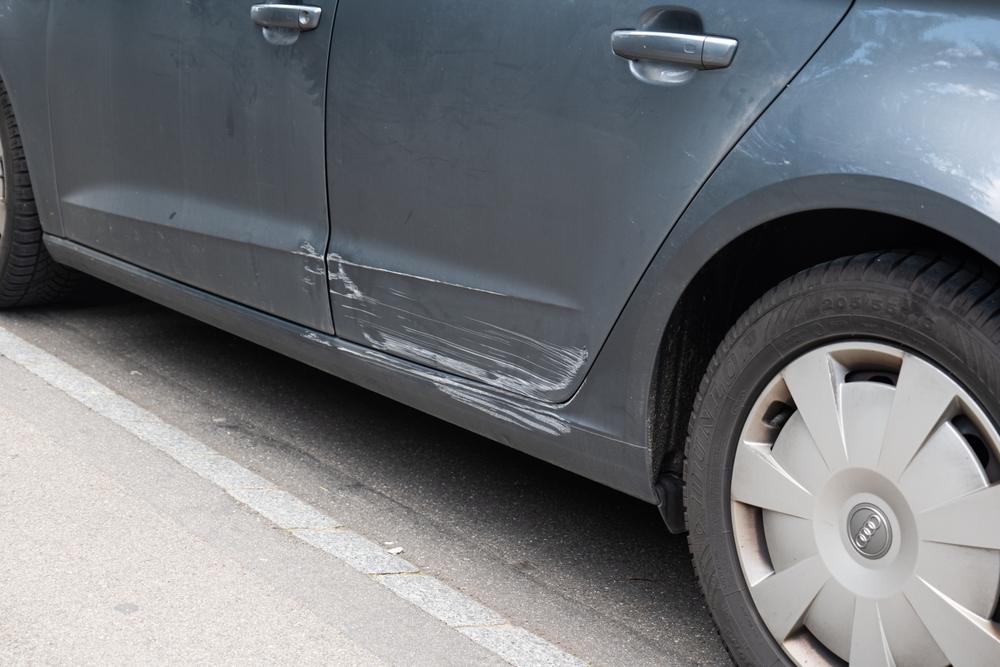 A close-up image of a scratched car door depicts the kind of damage commonly sustained in a minor car accident.
