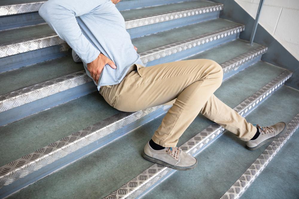 A man has fallen on stairs and holds his back. He is wondering what to expect in a slip and fall settlement without surgery.