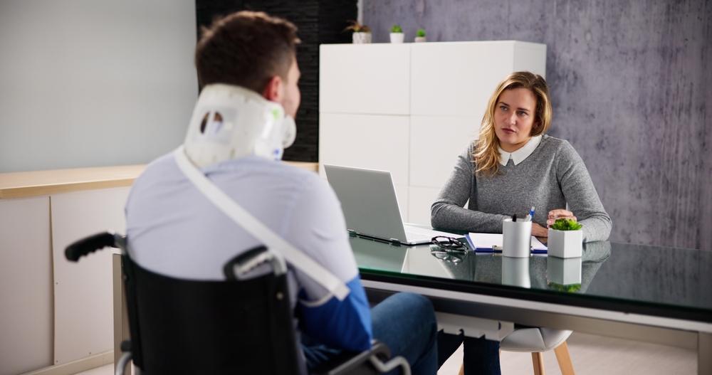 Injured man in neck brace and a sling sitting across from an attorney after learning what he should ask a truck accident lawyer.