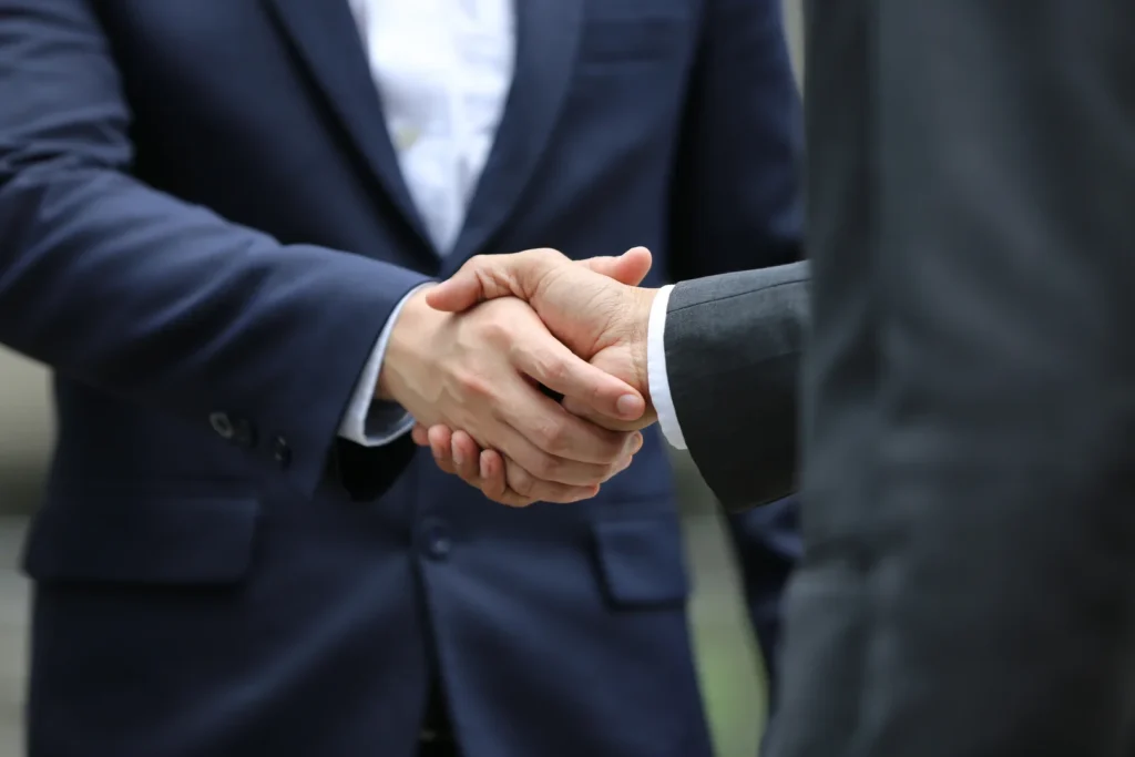 Two men in suits share a handshake